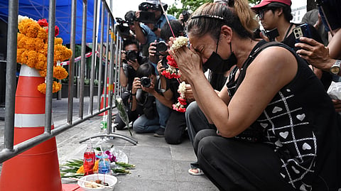A woman, identified as Nid, prays for her deceased daughter Namtip Tubsook and her son-in-law Suwitcha Sirililung in front of the Rong Beer Na Lat Phrao bar in Bangkok on July 14, 2026.