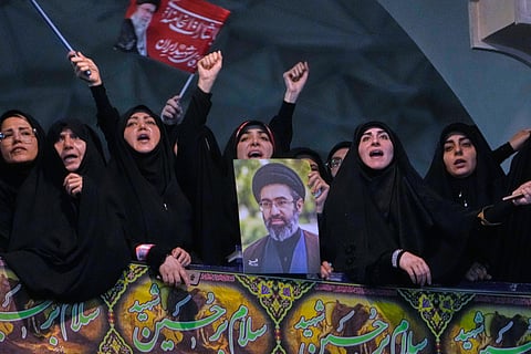 Mourners chant slogan as one of them holds a poster of the Supreme Leader Ayatollah Mojtaba Khamenei in a ceremony commemorating the late Supreme Leader Ayatollah Ali Khamenei at the Imam Khomeini Mosalla Grand Mosque in Tehran, Tuesday, July 14, 2026.