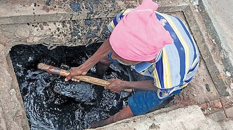 A sanitation worker clears a manhole without safety gear in the Mankammathota area of Karimnagar city on Tuesday.