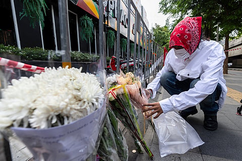 A man puts flowers outside the music bar where a fire killed a number of people in Bangkok, Thailand, Tuesday, July 14, 2026.