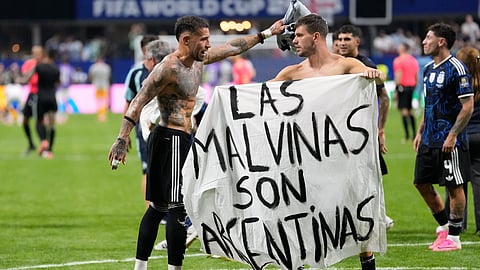 Argentina's Giovani Lo Celso holds a banner with the words "The Malvinas are Argentine", referring to the Falkland Islands, while teammate Argentina's Nicolas Otamendi gestures to him, at the end of the World Cup semifinal soccer match against England.