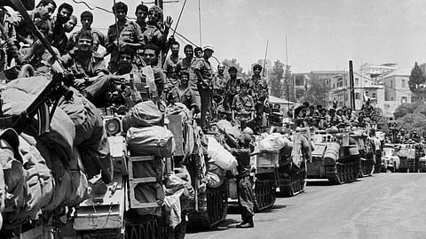 A long line of Israeli armoured personnel carriers and their crews wait on a street on the outskirts of Beirut, on July 27, 1982, for the order to proceed into the capital.