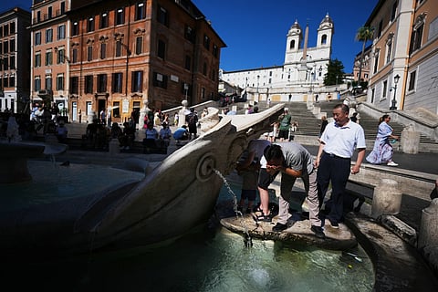People refreshes at the Barcaccia Fountain in front of Rome's Spanish Steps, Wednesday, July 15, 2026.