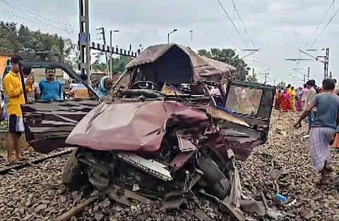 People gather as wreckage of a pool car, which was hit by a train at a level-crossing gate near the Karna Subarna Railway Station, lies on railway tracks, in Murshidabad district, West Bengal, Friday, July 17, 2026.