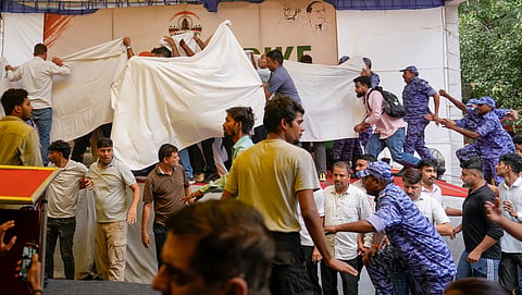 Security personnel screen with sheets and keep vigil as activist Sonam Wangchuk, unseen, who has been on an indefinite hunger strike for 21 days, is shifted to a hospital from Jantar Mantar, in New Delhi, Saturday, July 18, 2026. 