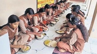 The students eating puffed rice along with curry for lunch.