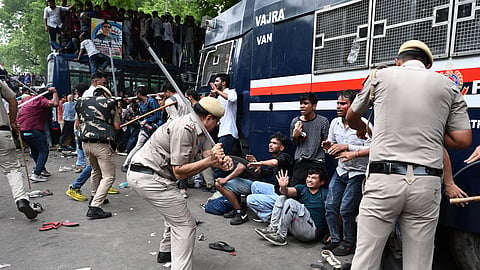 Security personnel hurling lathis at student protestors near Sansad Marg during the Parliament march called upon by Cockroach Janta Party members in New Delhi on Monday