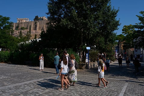 Tourists walk near the Acropolis  in Athens, Greece, Tuesday, July 21, 2026, after two tourists were stabbed and injured nearby in an attack on a pedestrian street near the entrance to the archaelogical site.