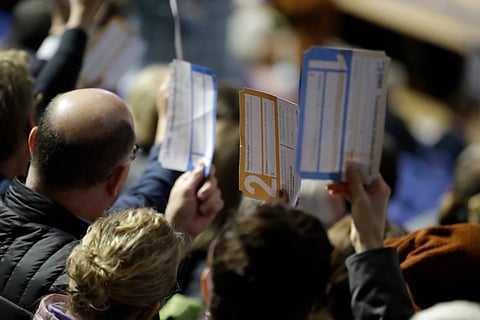 Precinct 68 Iowa Caucus voters seated in the Biden section hold up their first votes of the Caucus as they are counted at the Knapp Center on the Drake University campus in Des Moines, Iowa, Feb 3, 2020. 