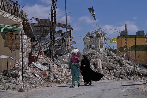 Lebanese women pass by houses that were destroyed in Israeli strikes during the war with Hezbollah in Froun village, southern Lebanon, Thursday, July 16, 2026. 