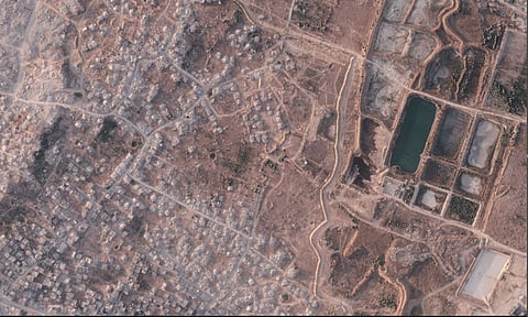 This satellite image from Planet Labs PBC shows a section of an earthen barrier being built by the Israeli military in the northern Gaza Strip, July 8, 2026. To the left is the demolished town of Beit Lahia, and at right a defunct sewage treatment plant