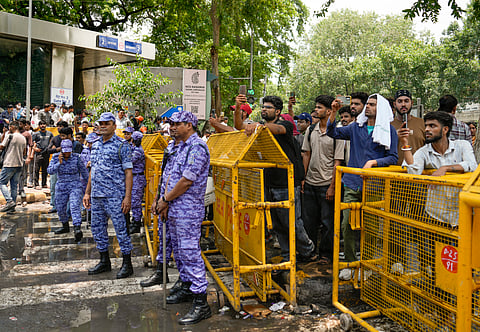 Security personnel stand guard as commuters gather outside Janpath metro station after it was closed due to 'security reasons', in New Delhi.