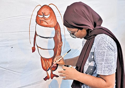 A girl paints a poster during the gathering at Manaveeyam Veedhi, expressing solidarity with the protest in New Delhi.