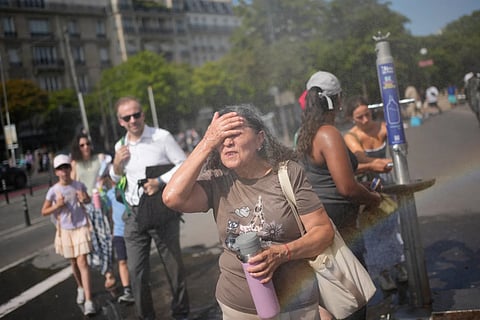 Tourists enjoy cooling off at a public water fountain in Paris, Friday, June 26, 2026.
