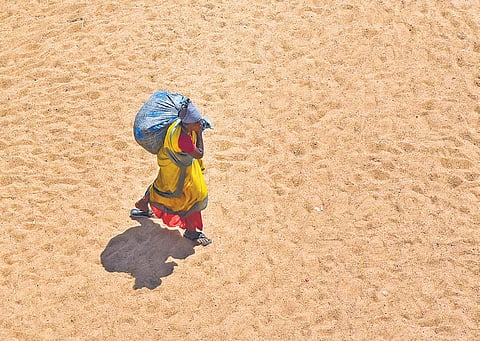 A woman walks on the dry riverbed of the Cauvery in Tiruchy on Friday.