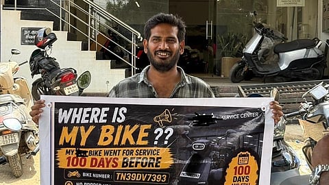Santhosh Kumar stands with a poster in front of the showroom
