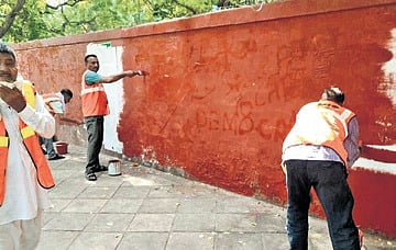 Workers remove graffiti on a wall in the Janpath area on Sunday 