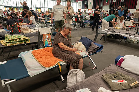 A woman caresses her pet dog at an emergency shelter set up in the Bordeaux Exhibition Centre in Bordeaux, France, for those that had to leave their homes outside town due to the raging wildfires, Sunday, July 26, 2026. 