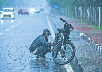 A man repairs his cycle after it breaks down amid heavy rain 