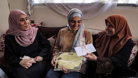 Palestinian highschool student Saba Rabah (C), the top-ranked student in the science stream of the Palestinian national high school exams, celebrates with family at the Maghazi camp for Palestinian refugees in the central Gaza Strip on July 26, 2026.