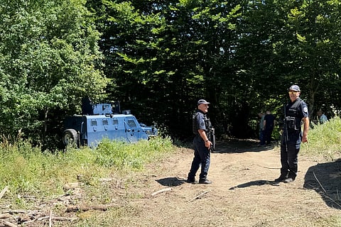 A Kosovo policemen guards the site where forensic teams have begun excavations of a mass grave near the village of Kalluder, Wednesday, July 29, 2026.