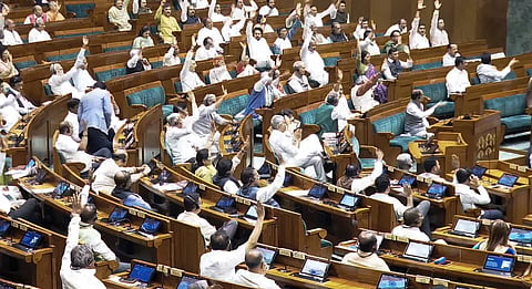 Lok Sabha members raise their hands during the passing of a bill in the House amid opposition protests.
