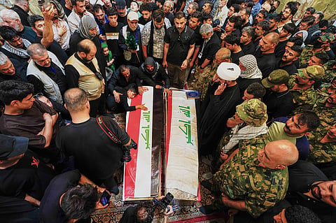 Mourners gather around the coffins of Popular Mobilization Forces fighters as a child rests on one of them during the funeral of those killed in airstrikes on PMF bases in Najaf, Iraq, Thursday, July 30, 2026. 