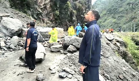 Relief team personnel escorting devotees across a safe passage on the Char Dham Yatra route in Uttarakhand.