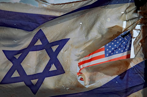 A U.S. flag is seen through a hole torn in an Israel national flag, as they wave in the wind at a horse ranch, near the southern Israeli town of Sderot, Friday, Nov. 20, 2020. 