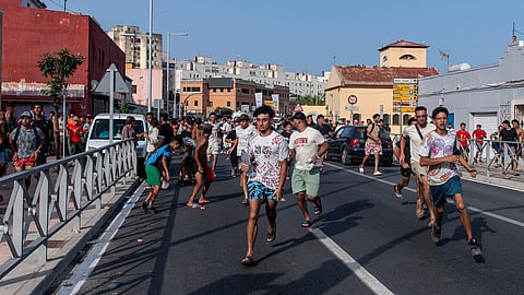 Migrants run from Spanish police officers after crossing from Morocco into the Spanish enclave of Ceuta, Friday, July 31, 2026. 