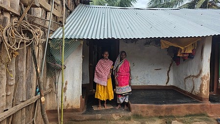 Savithri infront of the house refurbished using her earnings in Raipada village~Savithri of Raipada hamlet in Odisha who has worked as a migrant labourer in Kerala~Nanajya Pradhan, the Sarpanch of Danekbadi panchayat, who has worked as a migrant labourer