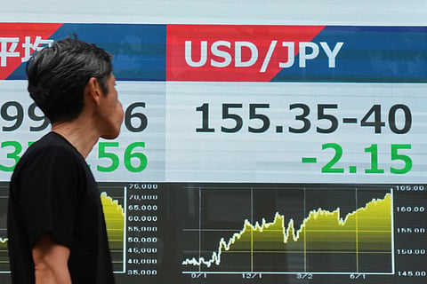 A person walks past an electronic board showing the US dollar and Japanese yen exchange rate at a securities firm in Tokyo on Monday, August 3, 2026.