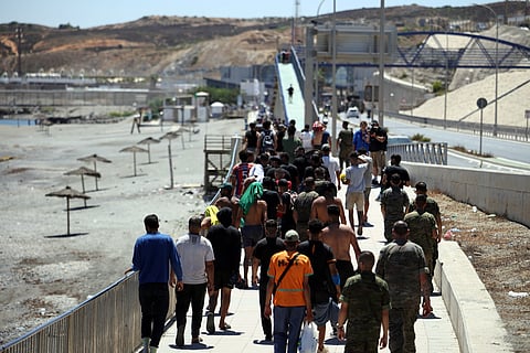 A group of migrants approach the border post to make their way back to Morocco, escorted by Spanish infantry soldiers, in the Spain's north African enclave of Ceuta, on August 2, 2026.