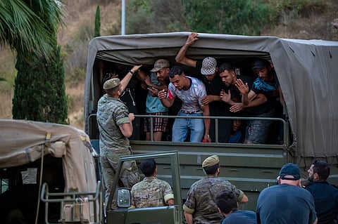 Migrants who crossed into Spain are escorted by Spanish soldiers towards the Spanish-Moroccan border for their return to Morocco from the Spanish enclave of Ceuta, Sunday, Aug. 2, 2026.