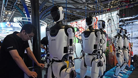 A worker reacts near a line of humanoid robots displayed at the World AI Conference in Shanghai, Friday, July 17, 2026. 