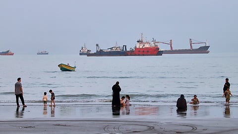 People spend time at a beach as commercial vessels are anchored in the Strait of Hormuz off Bandar Abbas, Iran, Wednesday, Aug. 5, 2026. 