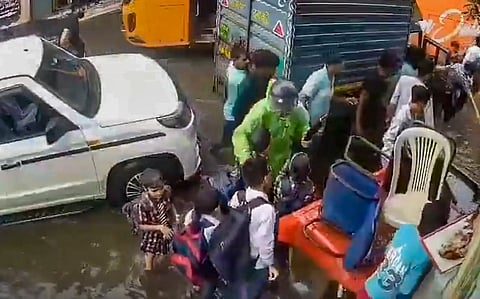 People gather after three schoolchildren fell into an open drain submerged by rainwater in Jagatpur village, in New Delhi, Thursday, Aug. 6, 2026