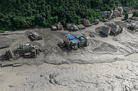 Damaged houses stand precariously near the swollen, debris-choked banks of the Trishuli River after flash floods in Nepal's Nuwakot district on Wednesday, Aug. 26, 2026.