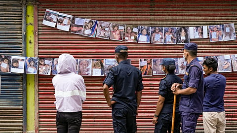 Family members look at posters displaying details of people who died in the floods, outside a hospital mortuary, in Kathmandu, Nepal
