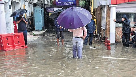 People standing on a waterlogged street near Connaught Place last week 