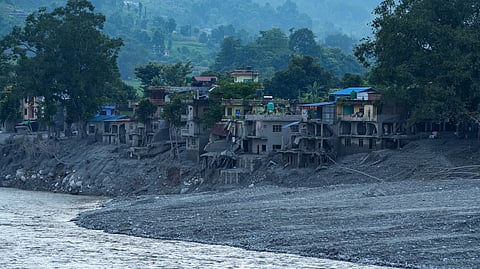 Damaged structures stand alongside a swollen river following devastating flash floods at Devighat, in Nuwakot district, Nepal, Saturday, Aug. 29, 2026.