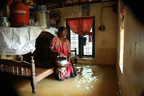 A woman sits inside her house, immersed in floodwater in Kerala's Ernakulam district in 2018