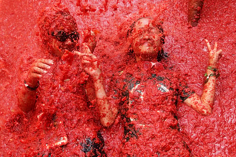 Revelers throw tomatoes at each other during the annual "Tomatina" tomato fight fiesta, in the village of Bunol near Valencia, Spain, Wednesday, Aug. 26, 2026.