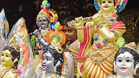 A child peeps though the Idols of Lord Krishna