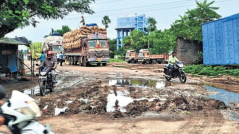 Motorists navigate large pools of water on an unmetalled road in Warangal