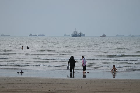 People spend time at a beach as commercial vessels are anchored in the Strait of Hormuz off Bandar Abbas, Iran, Wednesday, Sept. 2, 2026.