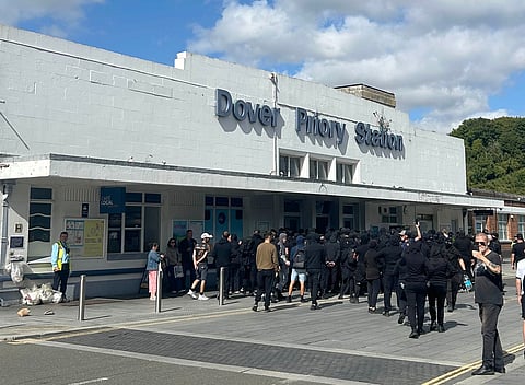 Protesters gather at Dover Priory train station after black-clad and masked demonstrators blocked roads during a protest, in Dover, England, Saturday, Sept. 5, 2026.