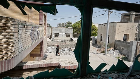 A person walks past debris, seen through a shattered window at the site of what Iranian media said was a U.S. strike on a home where a wedding celebration was being held late Tuesday, Sept. 1, in Kuhestak, southern Iran, Friday, Sept. 4, 2026.
