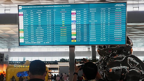 Travelers walk past an information board showing disrupted flights at Soekarno-Hatta International Airport in Tangerang, Indonesia, Sunday, Sept. 6, 2026. 