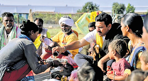 BJP state president BY Vijayendra shares a meal with a family of shepherds at Gangavathi before the Ballari Chalo padayatra on Sunday | Express